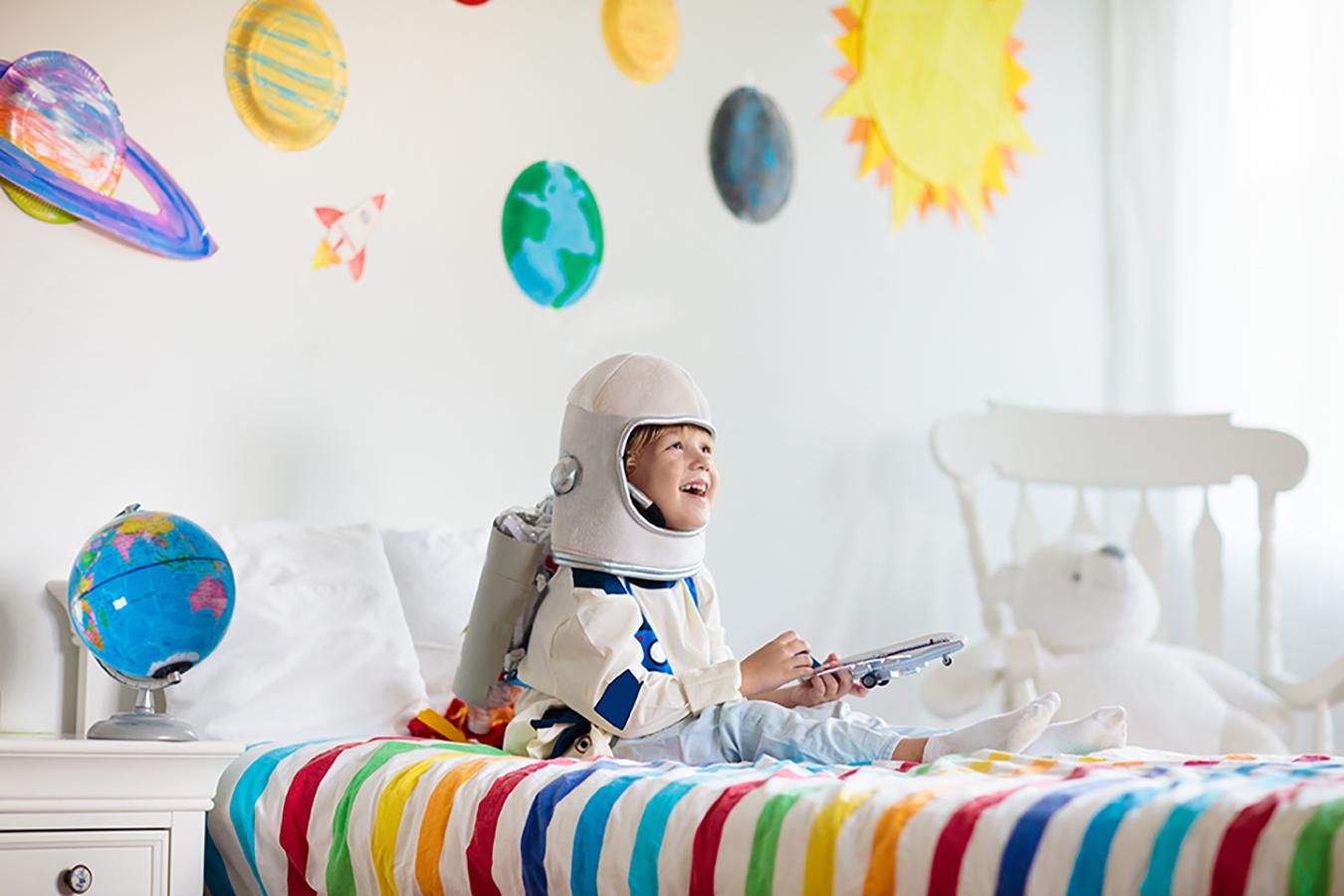 Junge im Astronauten Kostüm auf Bett